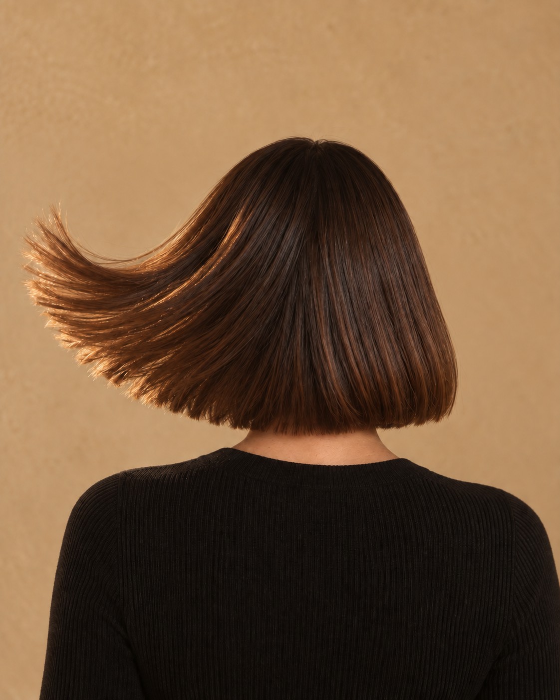 Femme au carré vue de dos, les cheveux balancés en arc vers la gauche